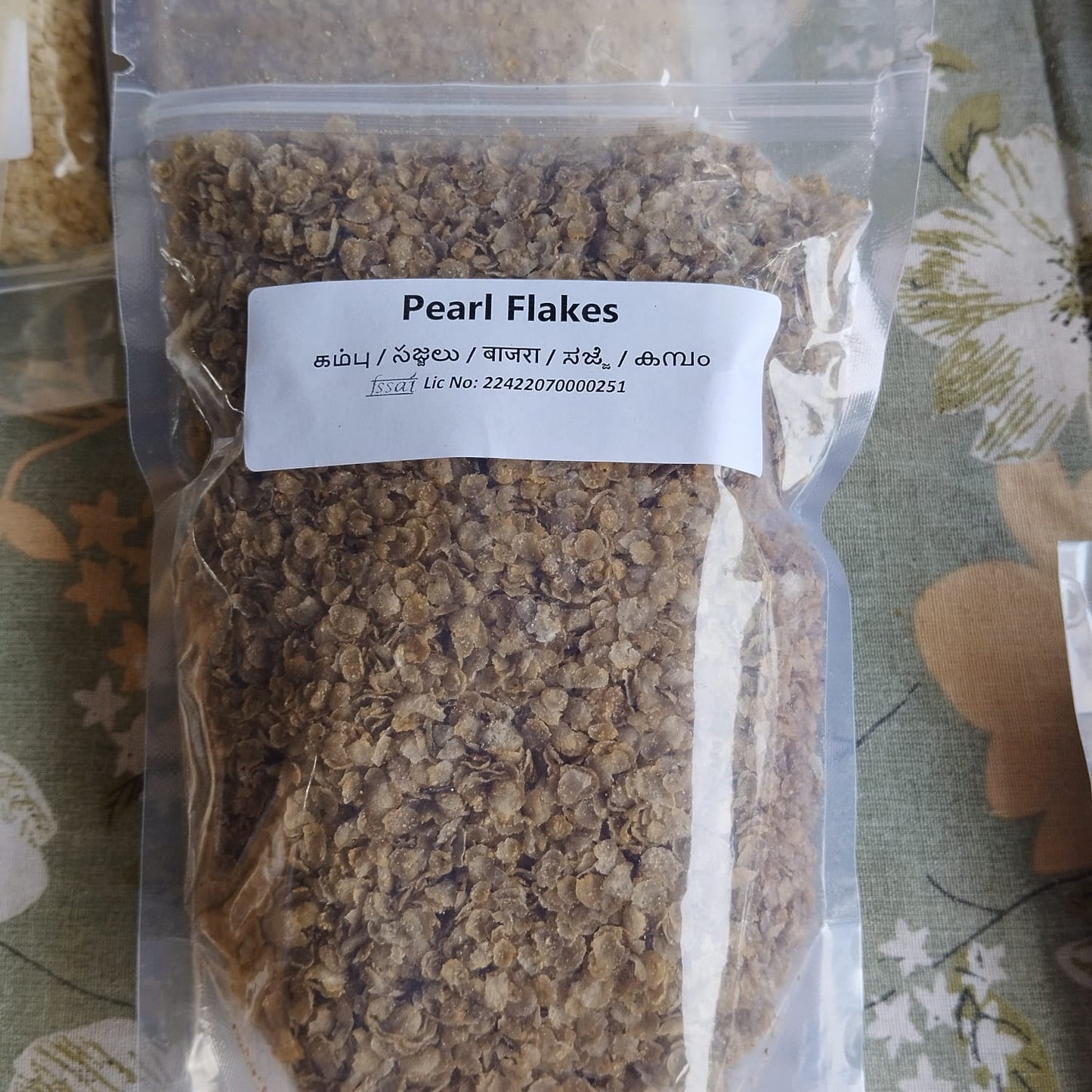 Packaged pearl flakes with a label on a floral-patterned surface, BKH Kambu Flakes, BKH Pearl millet Flakes