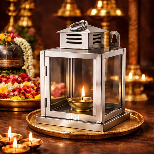 Metallic lantern with a lit candle on a wooden surface with decorative elements. BKH