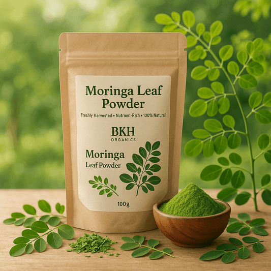 BKH Organics Moringa Leaf Powder package with green powder in a wooden bowl on a wooden surface with leaves. Murungai Leaf Powder 100g - BKH Organics