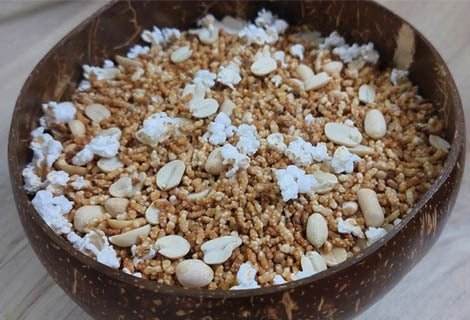 Coconut shell bowl filled with a mixture of white and brown granules on a light wooden surface. Pori arisi 300g - BKH Organics