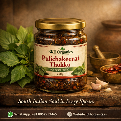 Jar of BKH Organics Pulichakeerai Thokku on a rustic wooden surface with leaves and garlic.