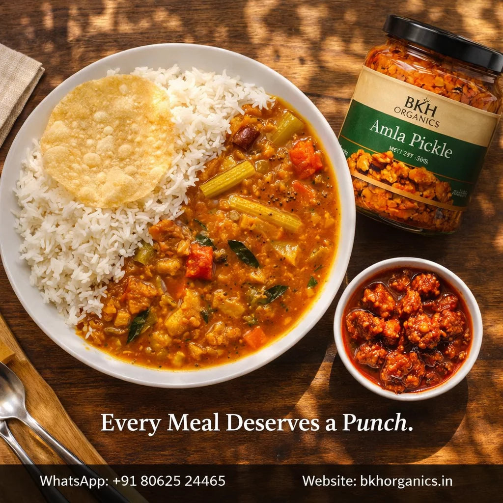 Curry with rice, Amla Pickle jar, and small bowl of pickle on a wooden table with 'BKH Organics' branding.
