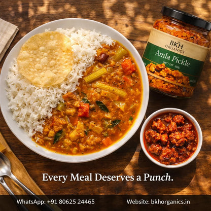 Curry with rice, Amla Pickle jar, and small bowl of pickle on a wooden table with 'BKH Organics' branding.