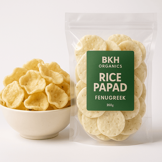 Bowl of rice papad next to a package labeled 'BKH Organics Rice Papad Fenugreek' on a white background
