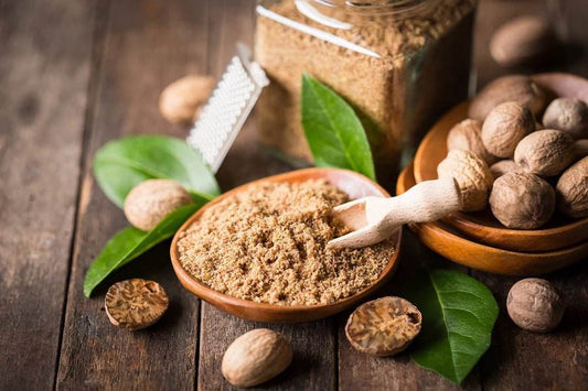 Brown sugar in a wooden bowl with nuts and leaves on a rustic wooden surface. Jathikai Herbal Powder 100g - BKH Organics