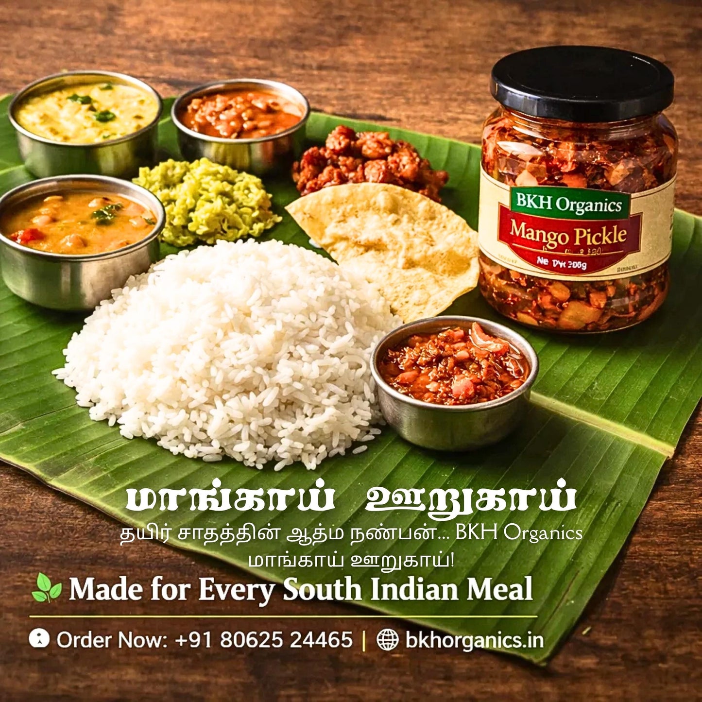South Indian meal setup with rice, pickles, and a jar of BKH Organics Mango Pickle on a wooden surface.