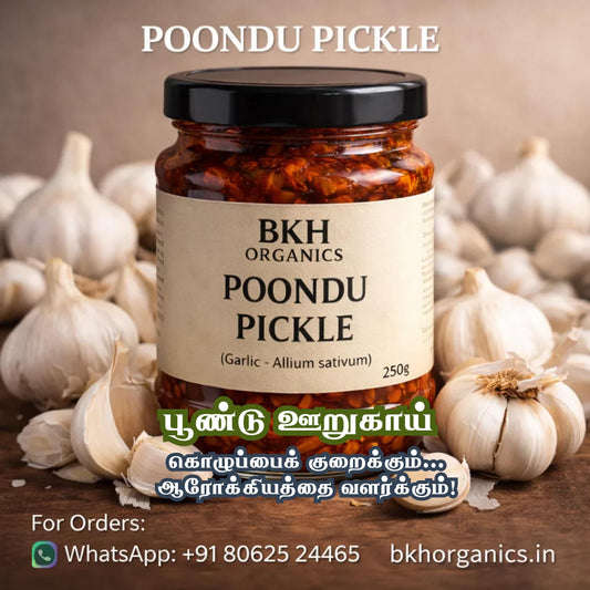 Jar of BKH Organics Poondu Pickle surrounded by garlic bulbs on a wooden surface.