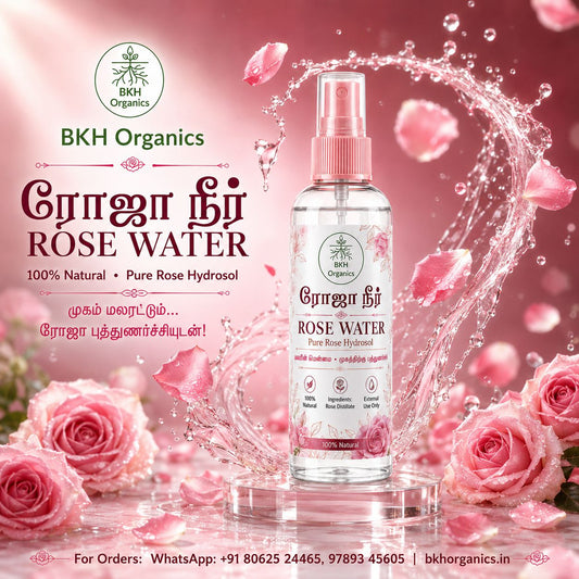 A bottle of BKH Organics Rose Water Pure Rose Hydrosol centered on a pink promotional background with rose petals, roses, and a water splash. The bottle is clear with pink spray top and pink floral graphics on the label.
