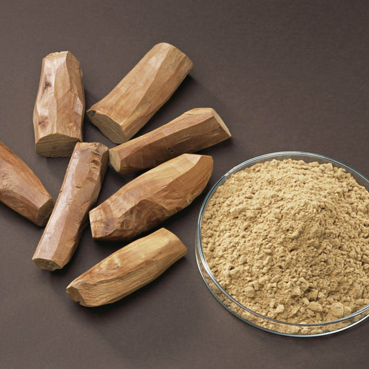 Wooden pieces and a bowl of Sandal wood brown powder on a dark background
