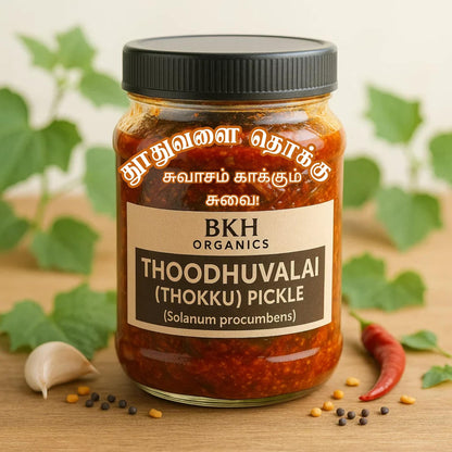 Jar of BKH Organics Thoodhuvalai (Thokku) Pickle with a label on a wooden surface with green leaves in the background.
