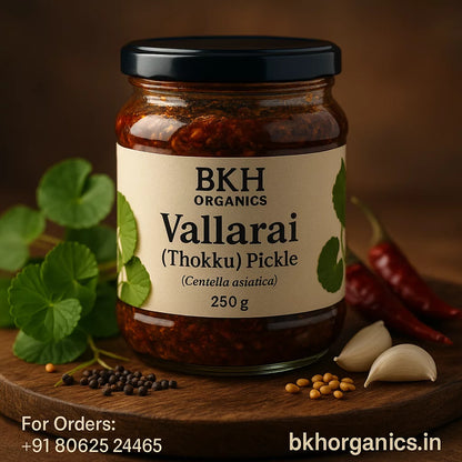 Jar of BKH Organics Vallarai Pickle on a wooden board with ingredients. Centella asiatica